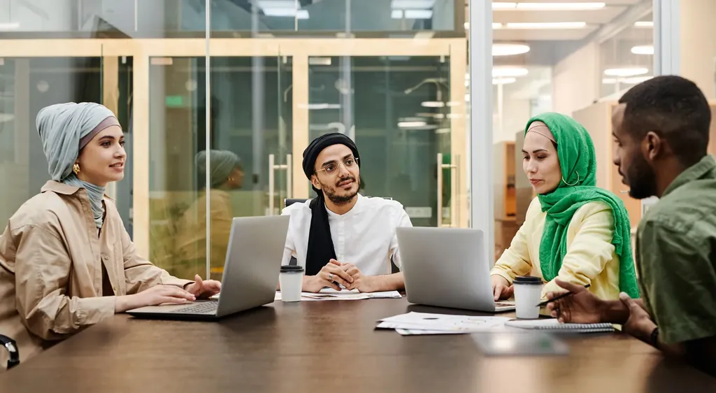Team meeting around a conference table with laptops