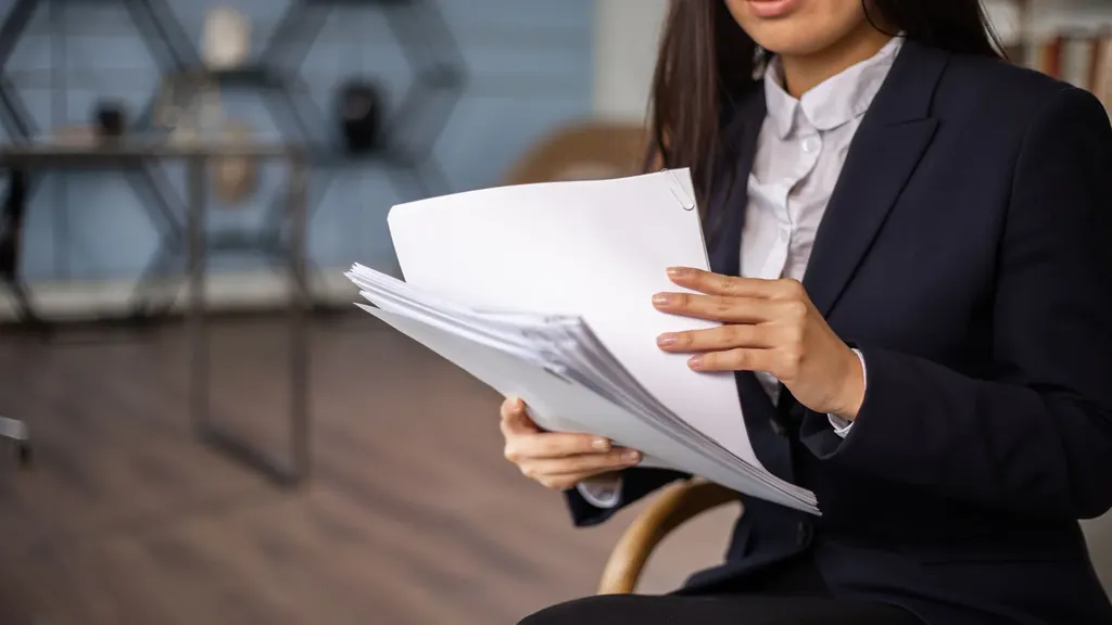 Professional in a blazer reviewing a stack of papers