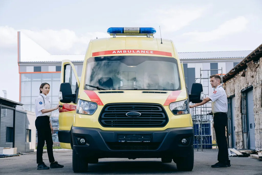 Two paramedics standing by a yellow ambulance with its doors open