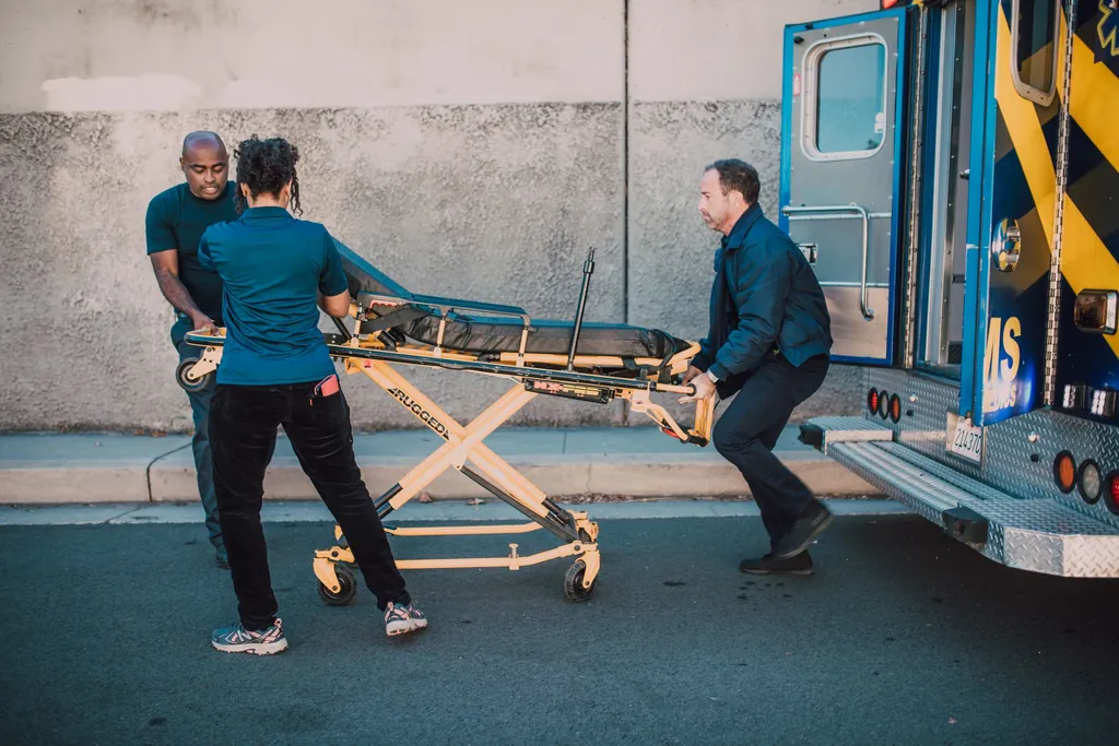 Paramedics pushing a stretcher toward an open ambulance