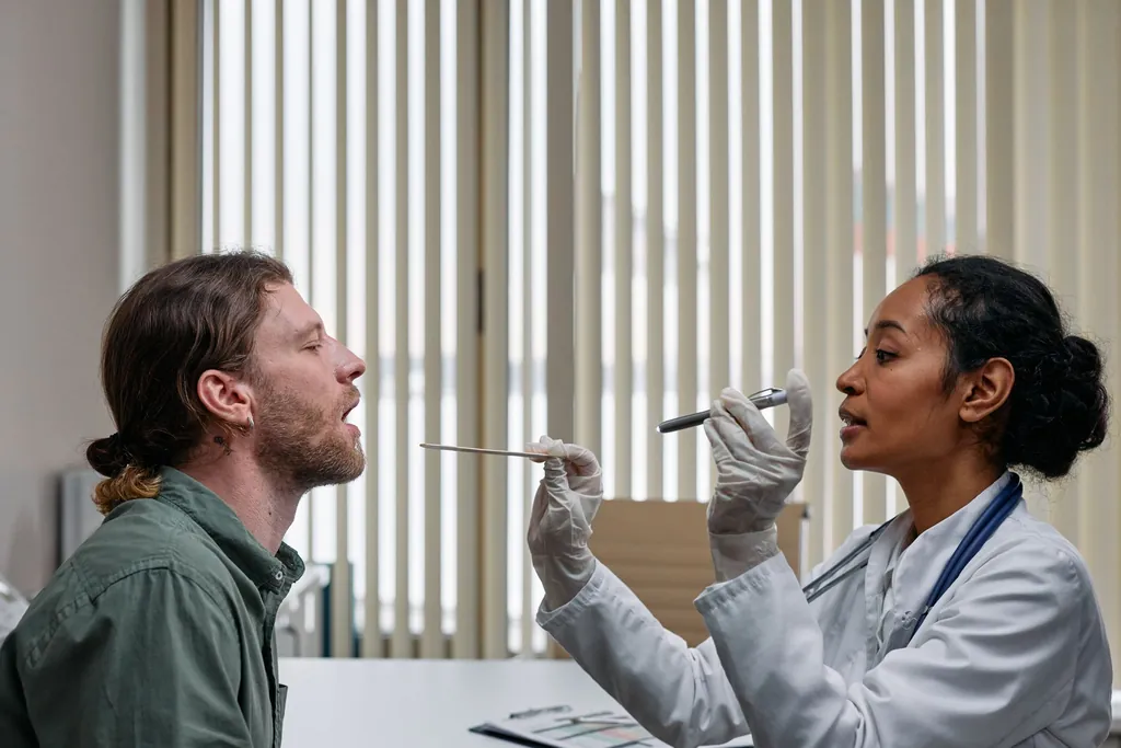 Physician examining a seated patient's throat in a clinic room