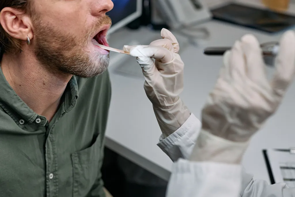 Gloved clinician holding a swab to a patient's open mouth