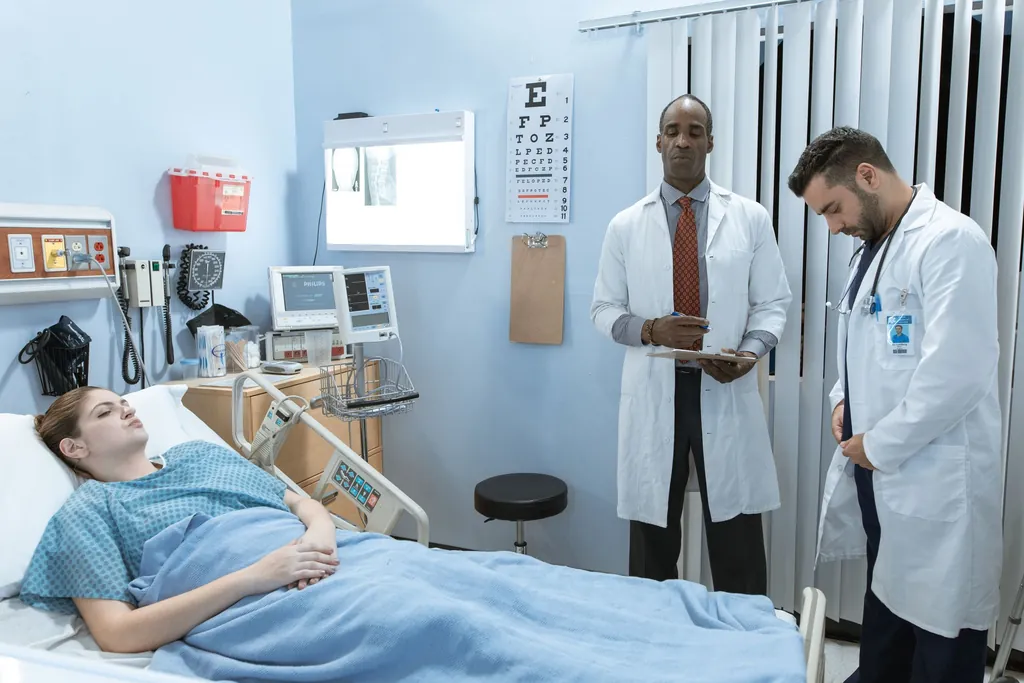 Two physicians talking beside a patient in a hospital bed