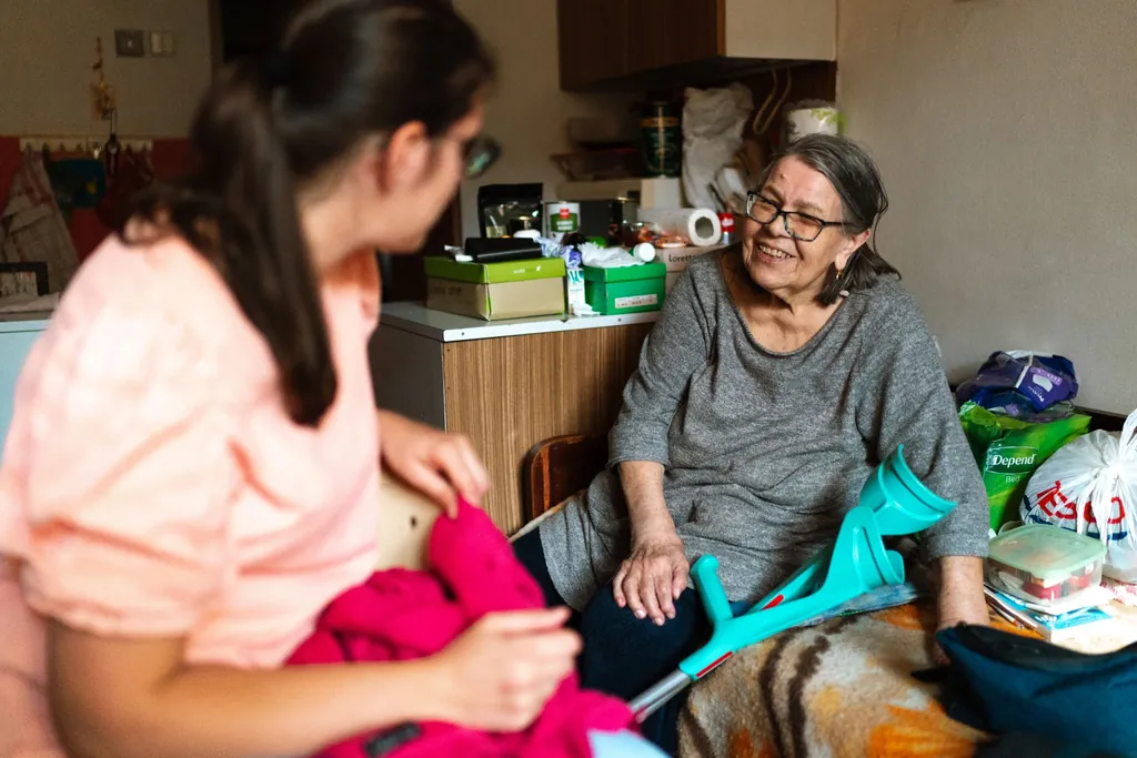 Caregiver chatting with an older woman in her home
