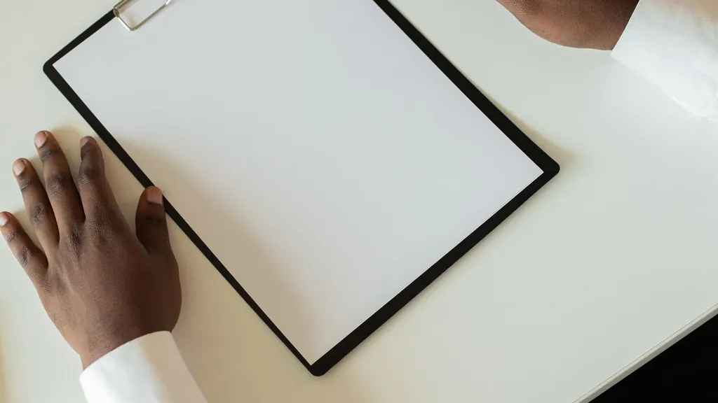 Hand resting on a blank clipboard