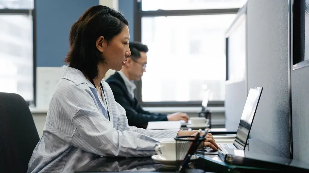 Office staff working at laptops by a window
