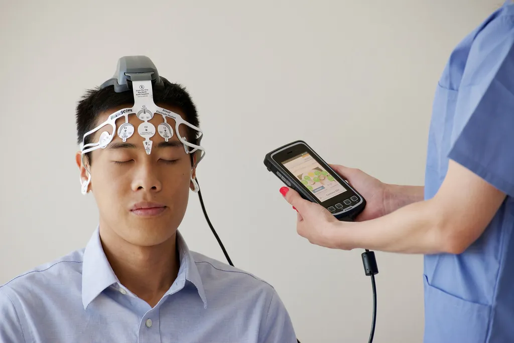 Patient wearing an EEG headset while a clinician checks a phone