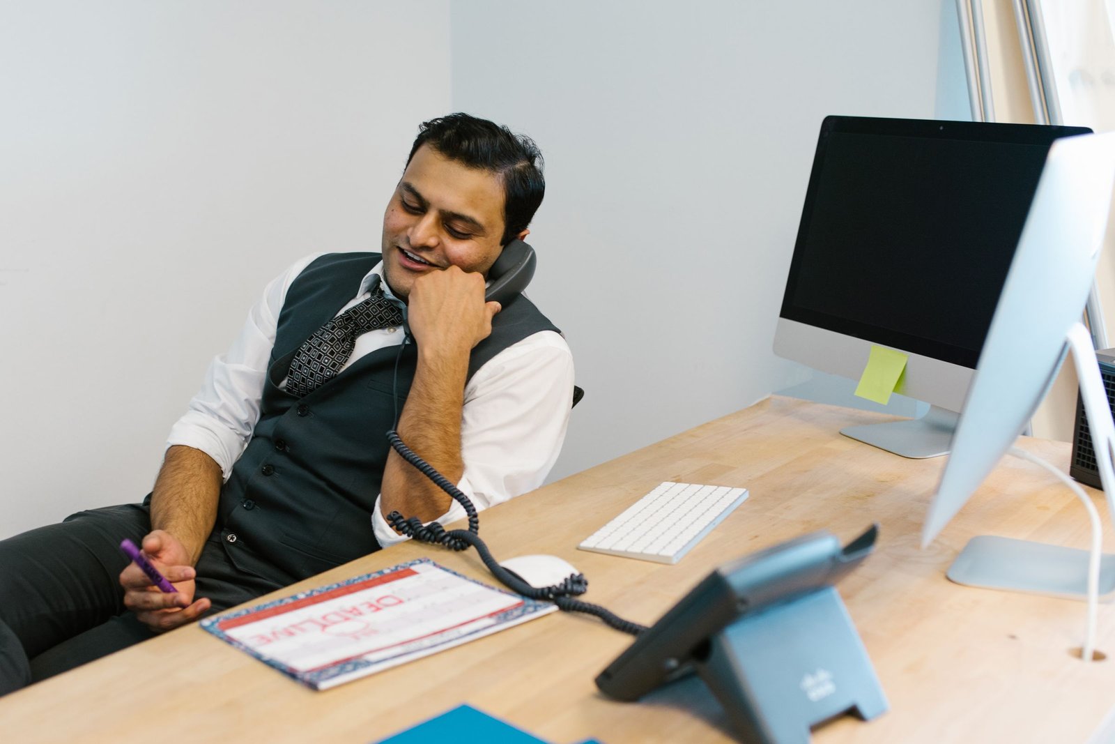 Billing specialist on a desk phone call with a printed report in front of him
