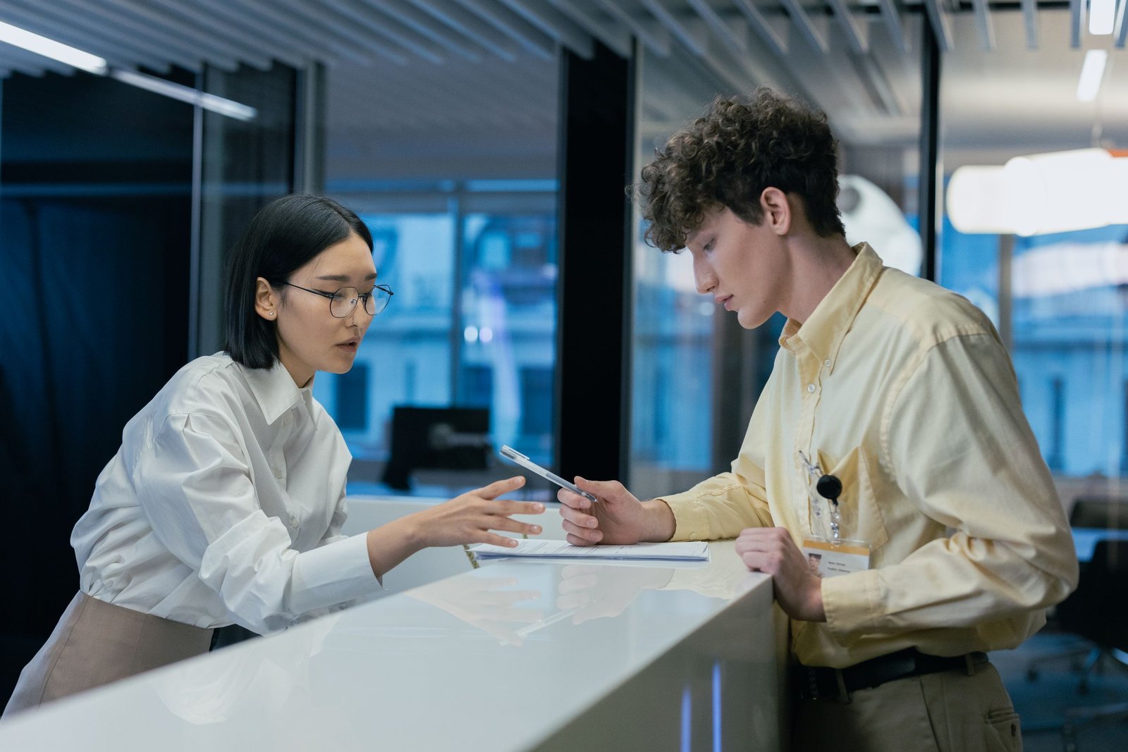 Front desk staff member helping a visitor fill out intake forms at the reception counter