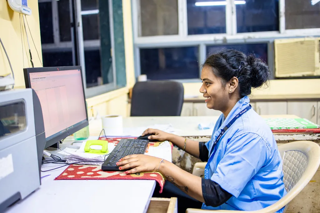 Clinic staff member in a blue uniform working at an office computer