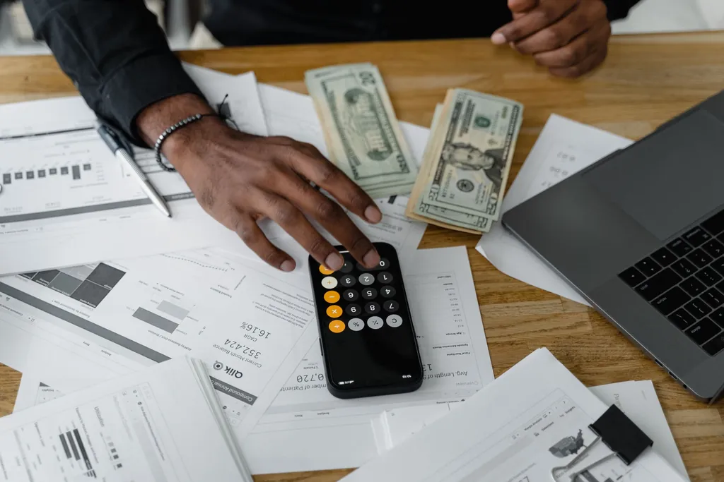 Hands using a calculator over printed bills and statements on a desk