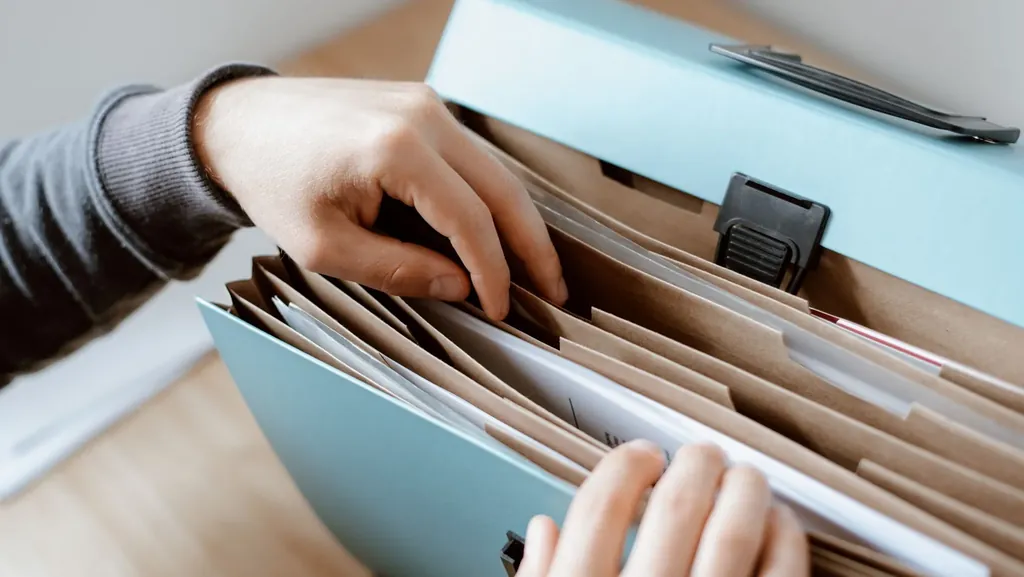 Hands sorting documents in a latched file box