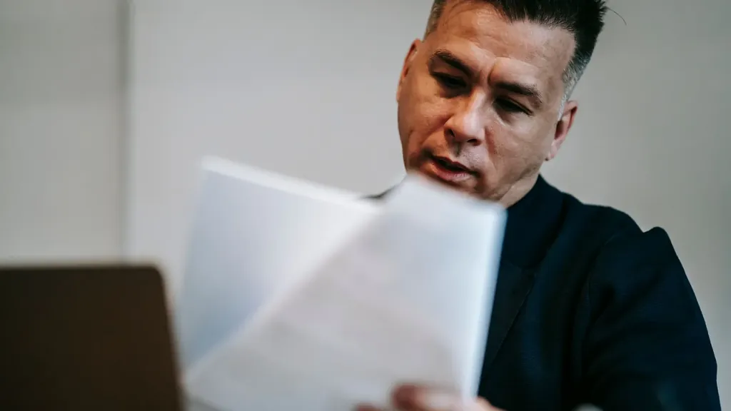 Man reviewing a stack of documents at his desk