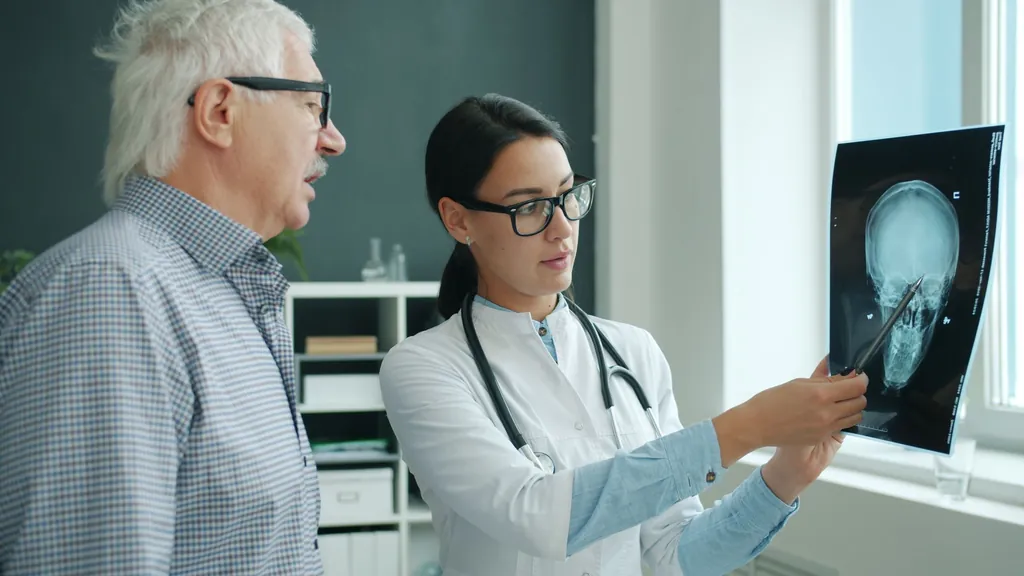 Physician showing a head scan on a screen to an older patient