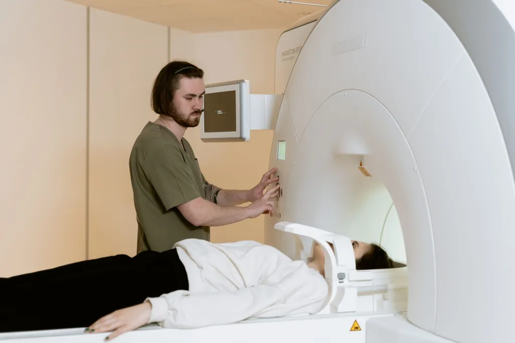 Technologist at the controls of an MRI scanner with a patient lying on the table
