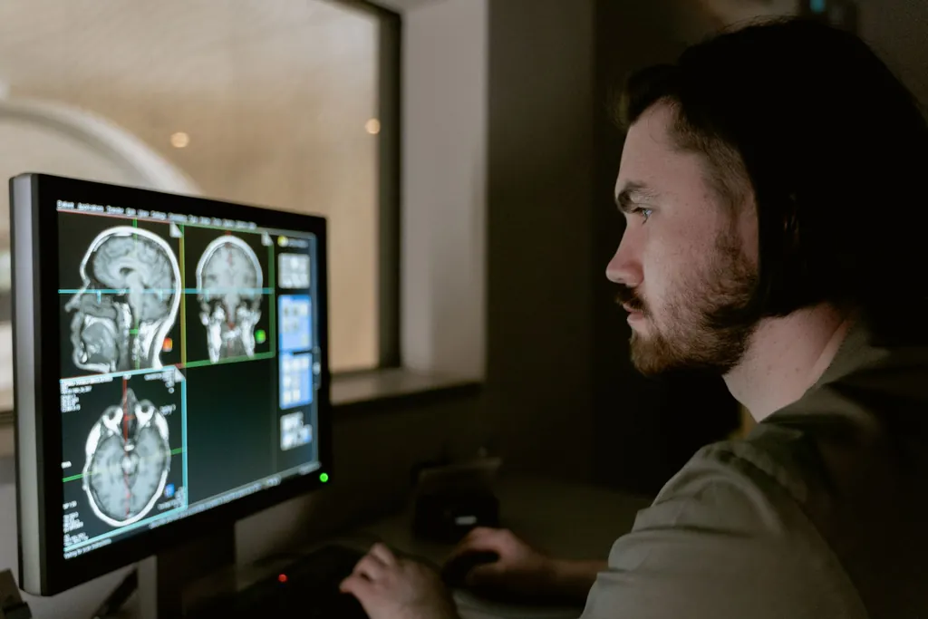 Radiologist reviewing brain MRI images on a monitor in a dim reading room