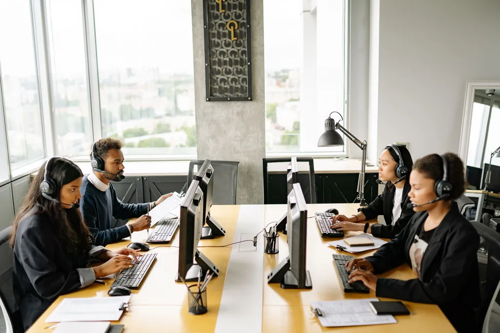 Team of office staff with headsets working at desks in a bright office