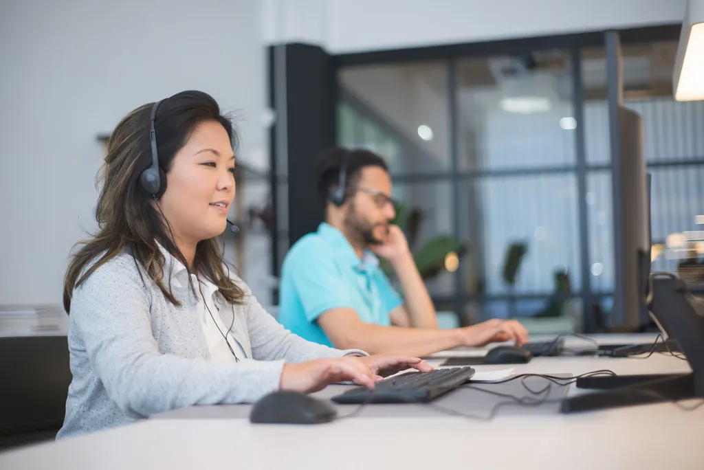 Two office staff with headsets working at their computers