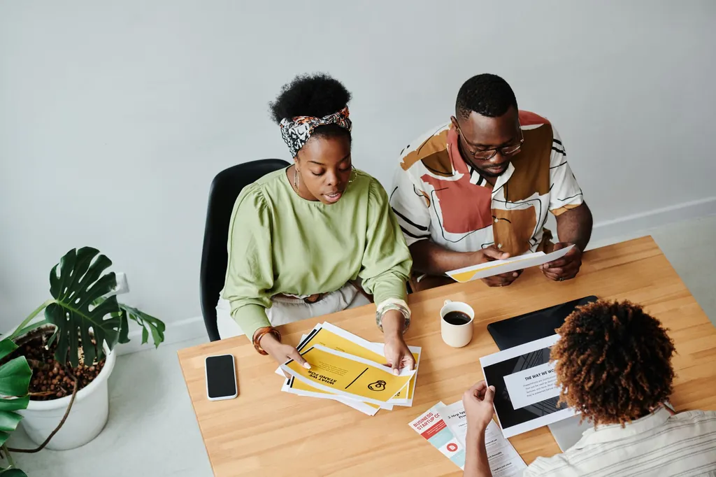 Three colleagues at a table going through printed documents together