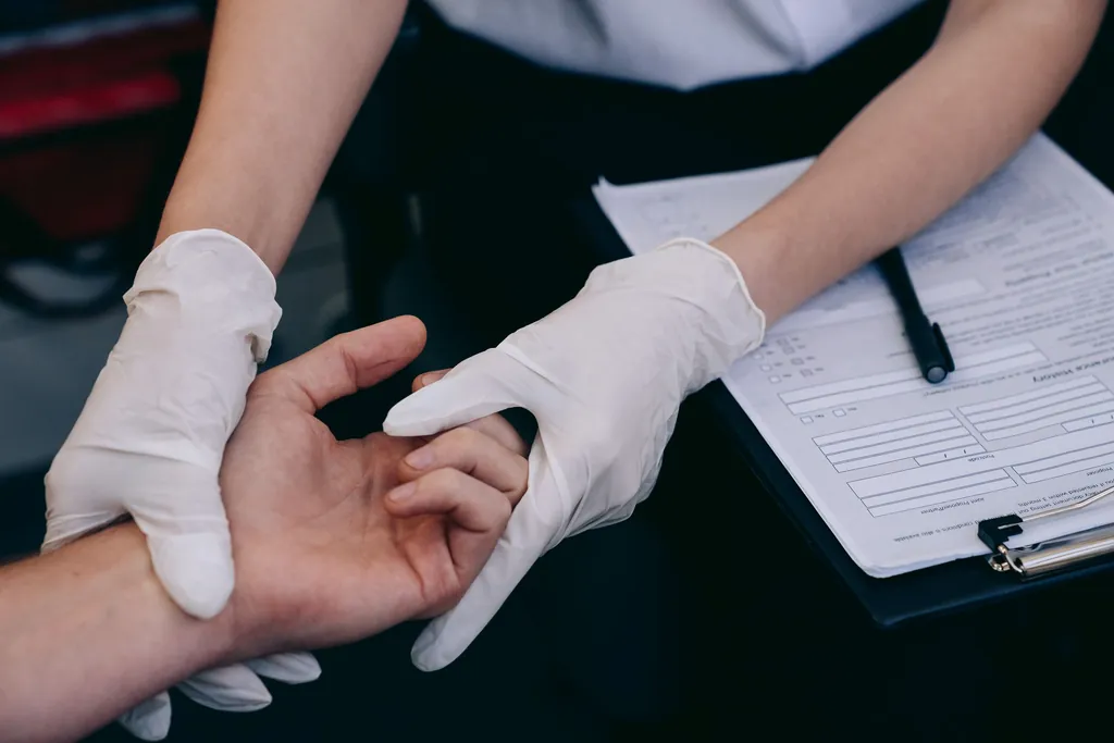 Gloved hands examining a patient's hand and wrist