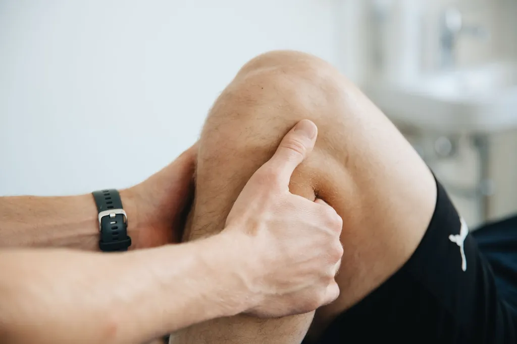 Clinician's hands pressing on a patient's knee during an exam