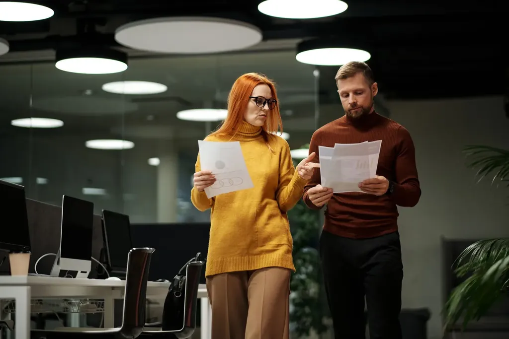 Two colleagues walking through the office reviewing papers