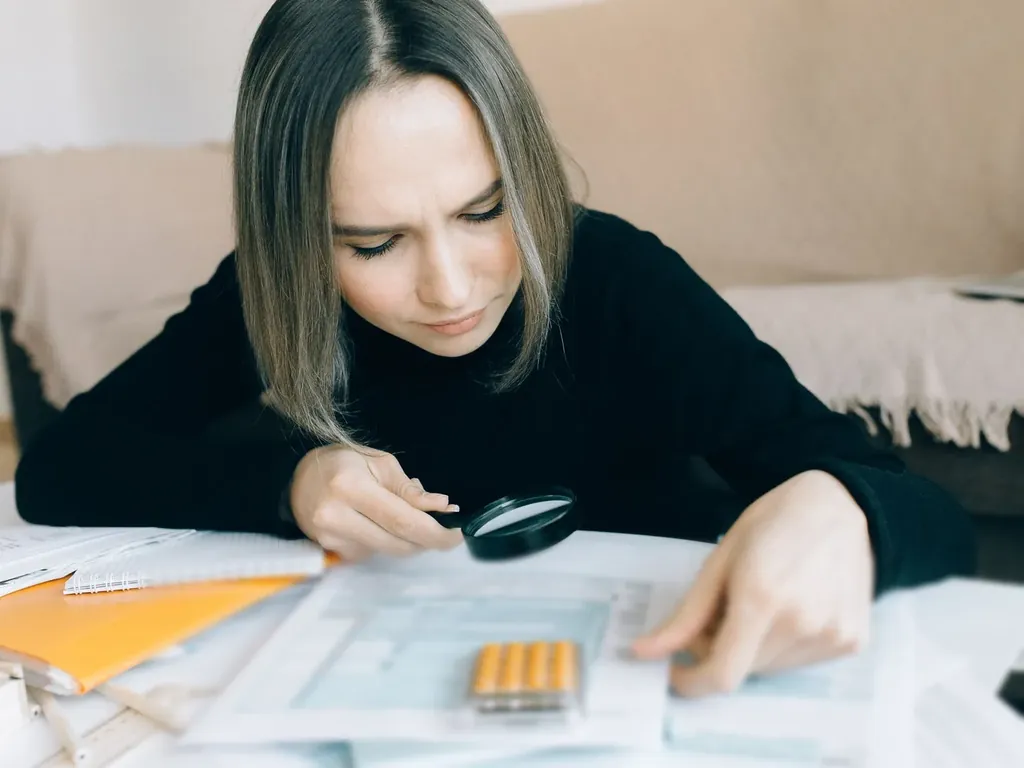 Woman checking a document closely with a magnifying glass