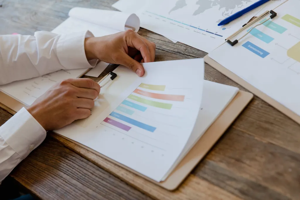 Hands holding a printed report with bar charts on a desk