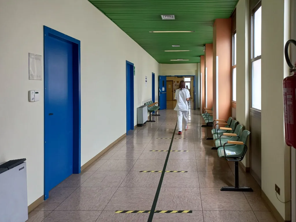 Woman walking down a long, bright hospital hallway