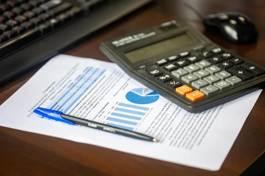Calculator, pen and a printed financial report with charts on a desk