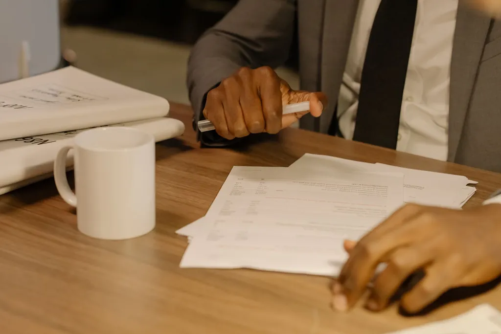 Hands resting on printed documents on a wooden desk
