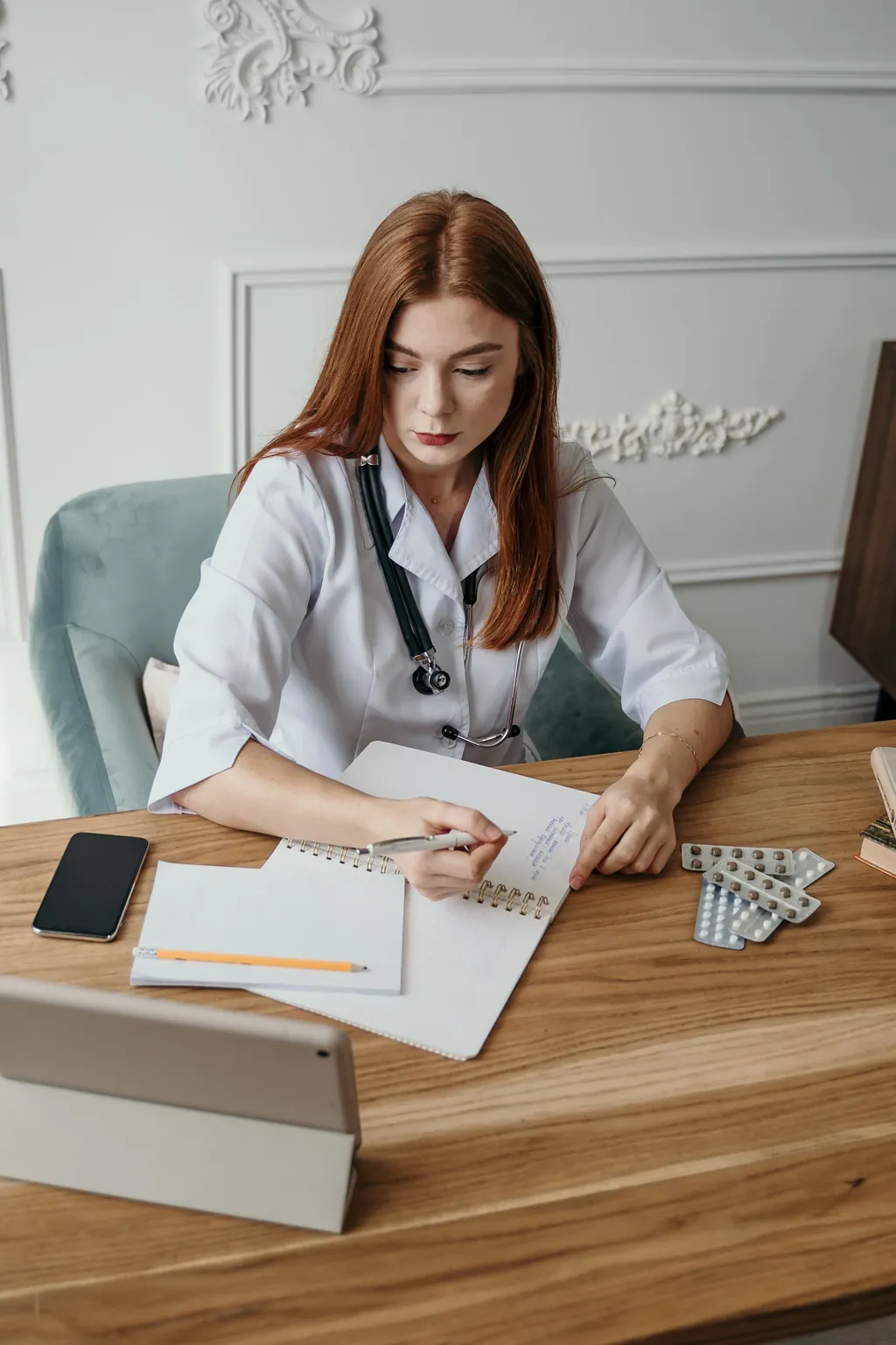 Provider reviewing notes at her desk beside a tablet and notebook