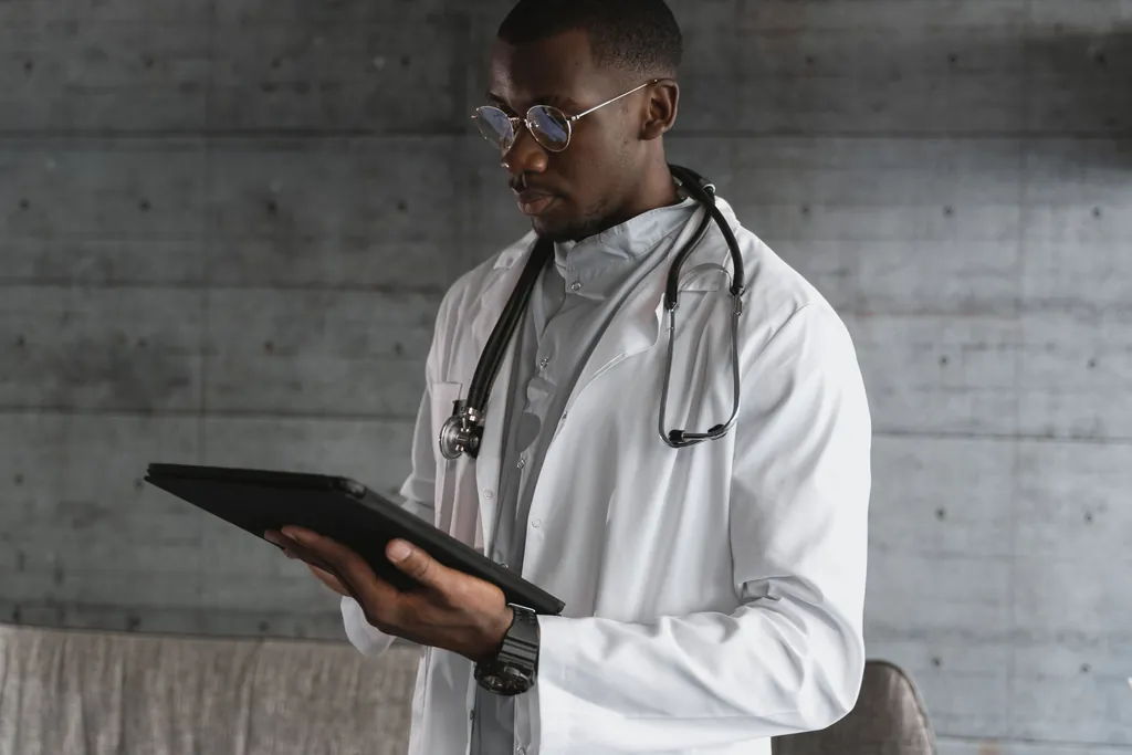 Physician in a white coat reviewing records on a tablet