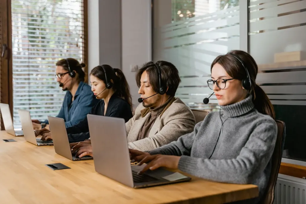 Billing team with headsets working at laptops in a bright office