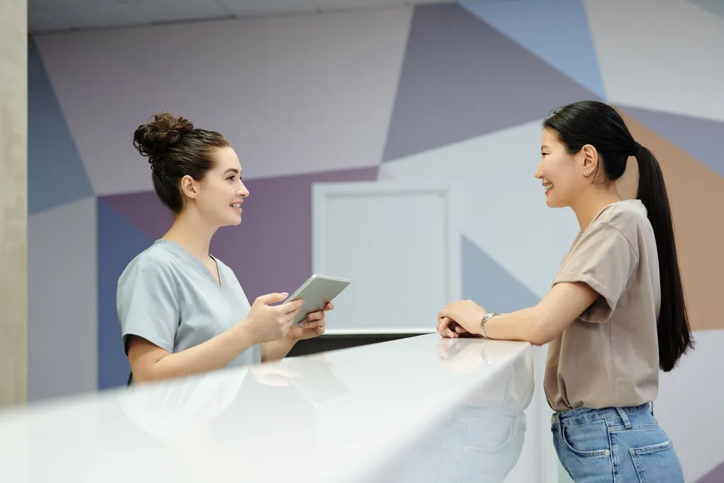 Front desk staff member with a tablet checking in a patient