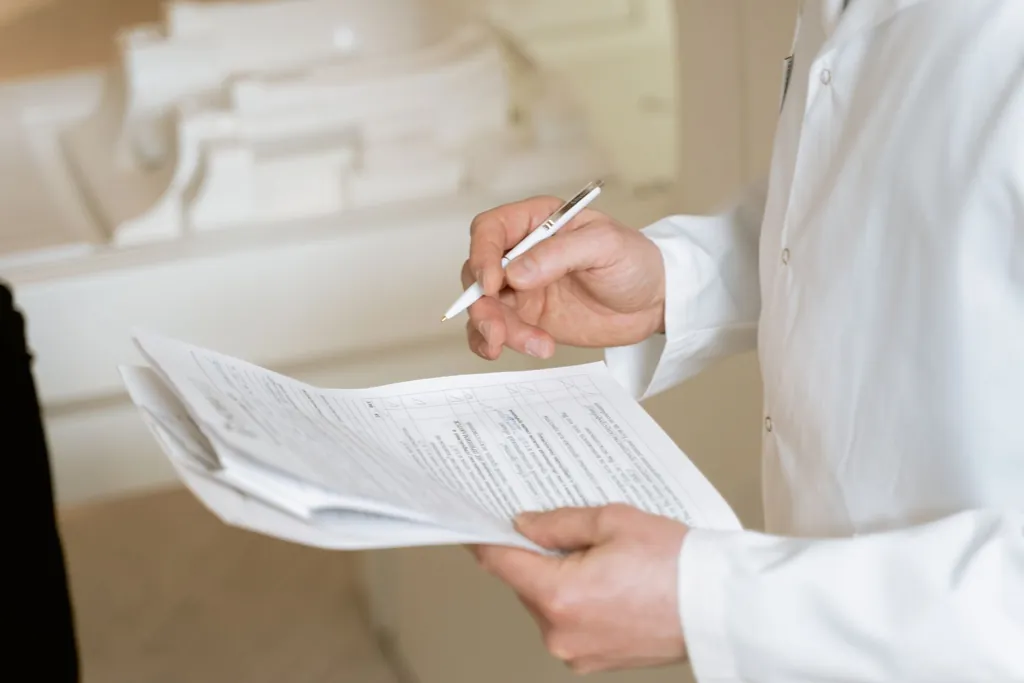 Person in a white shirt holding a pen and reviewing a printed document