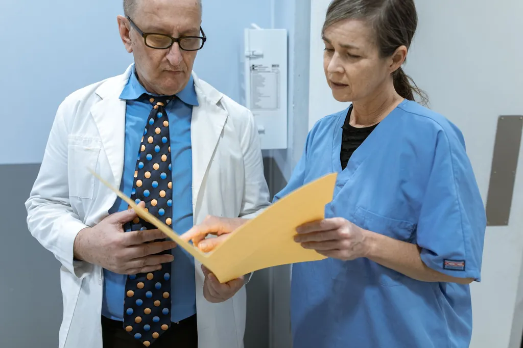 Doctor in a white coat and a nurse in scrubs reviewing a folder together