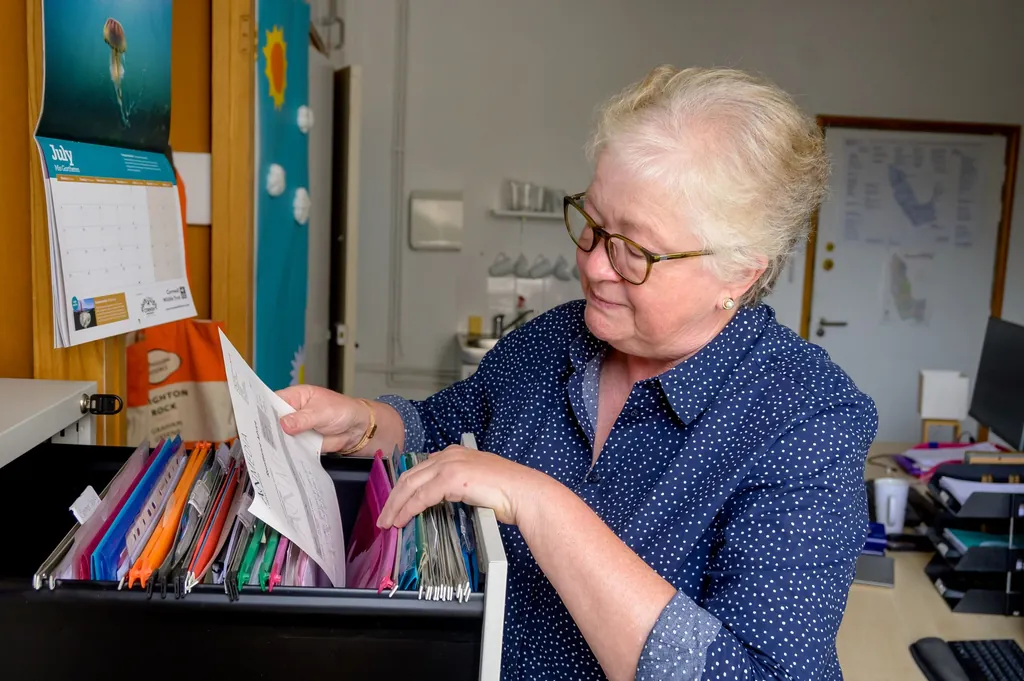 Older woman sorting through hanging files in a filing drawer