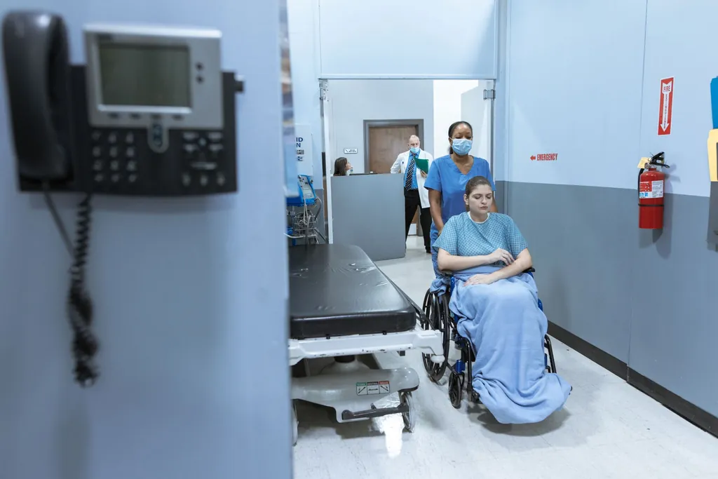 Nurse wheeling a patient in a wheelchair down a hospital corridor