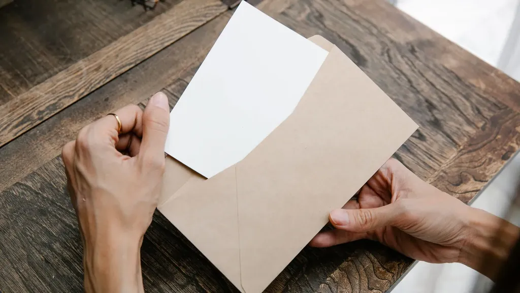 Hands pulling a sheet of paper from an envelope