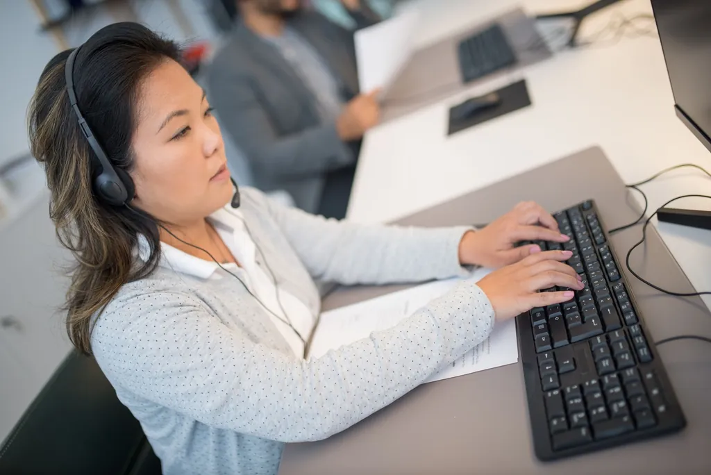 Billing specialist in a headset typing at her desk