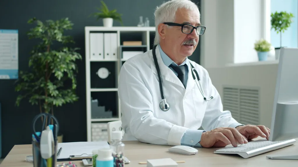 Physician working at a desktop computer in his office