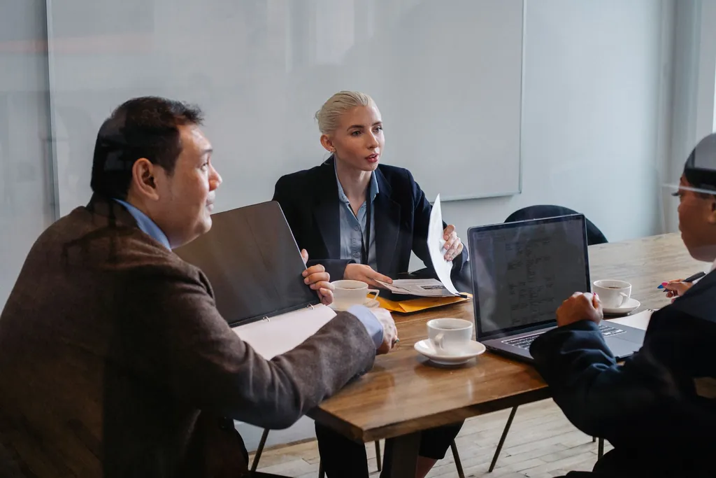 Coworkers discussing plans around a table with laptops and documents