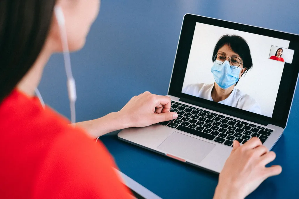 Person on a laptop video call with a doctor wearing a face mask