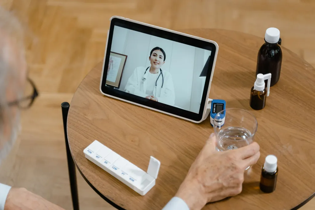 Tablet on a table showing a video call with a doctor, beside medicine bottles