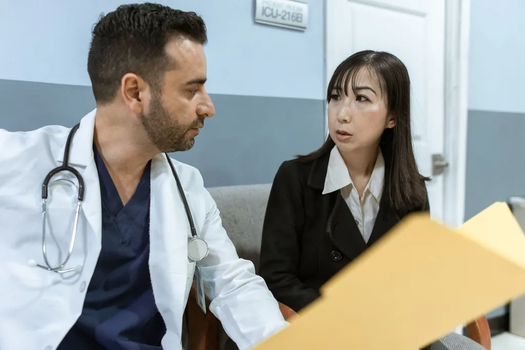 Physician in a white coat talking with a patient who holds a folder